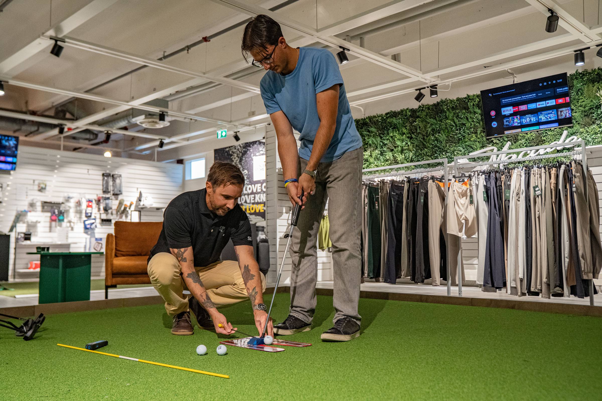 Två personer undersöker putter och uppställning på butikens puttingyta.